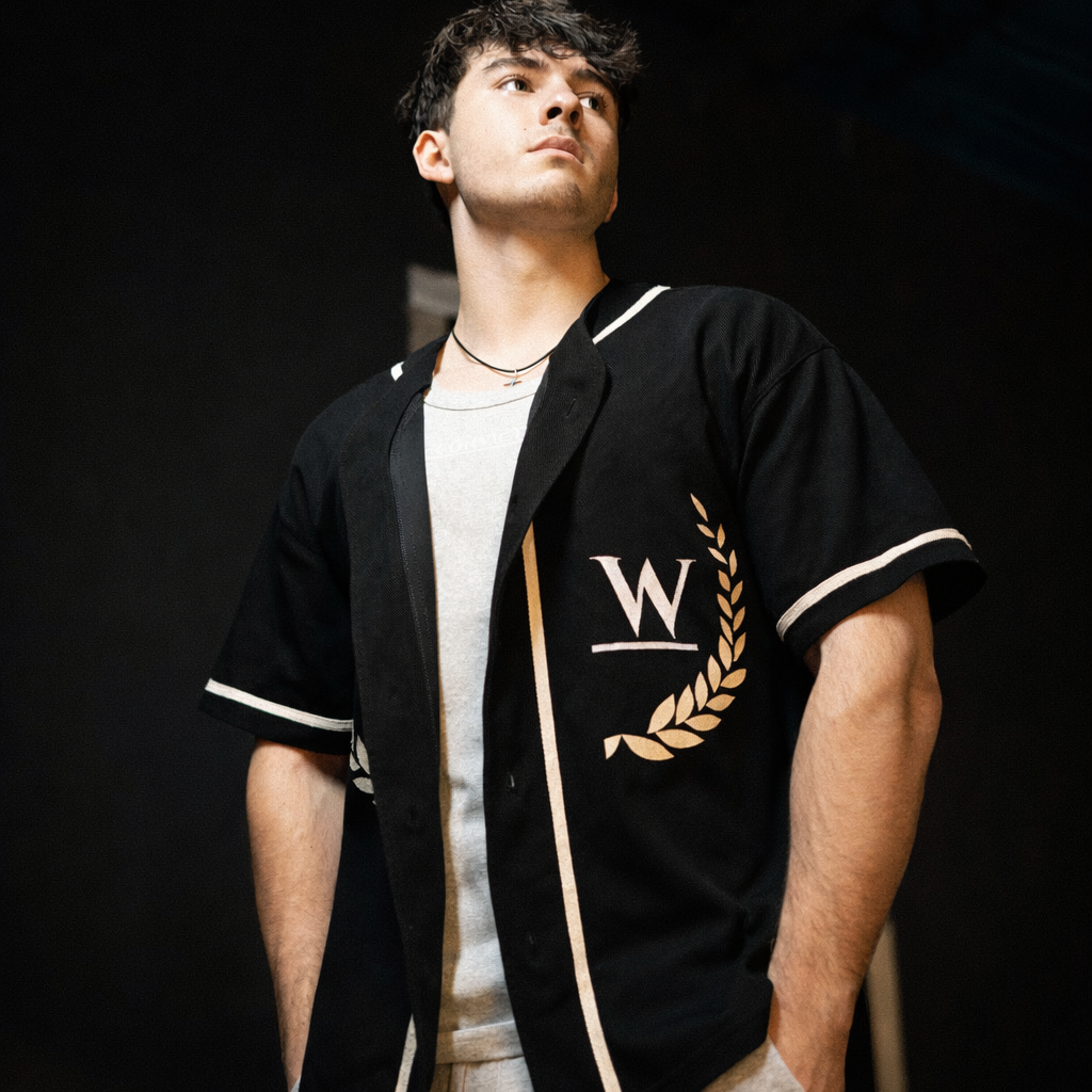Conviction black baseball jersey featuring white W logo and gold laurel wreath on chest